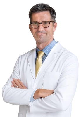 VTC_DrKindelan_Cutout_optimized Professional portrait of Dr. Walter Lech, a vein specialist, wearing a white lab coat and glasses, posed against a black background with arms crossed. This formal clinical headshot represents a healthcare provider specializing in vein treatment services.